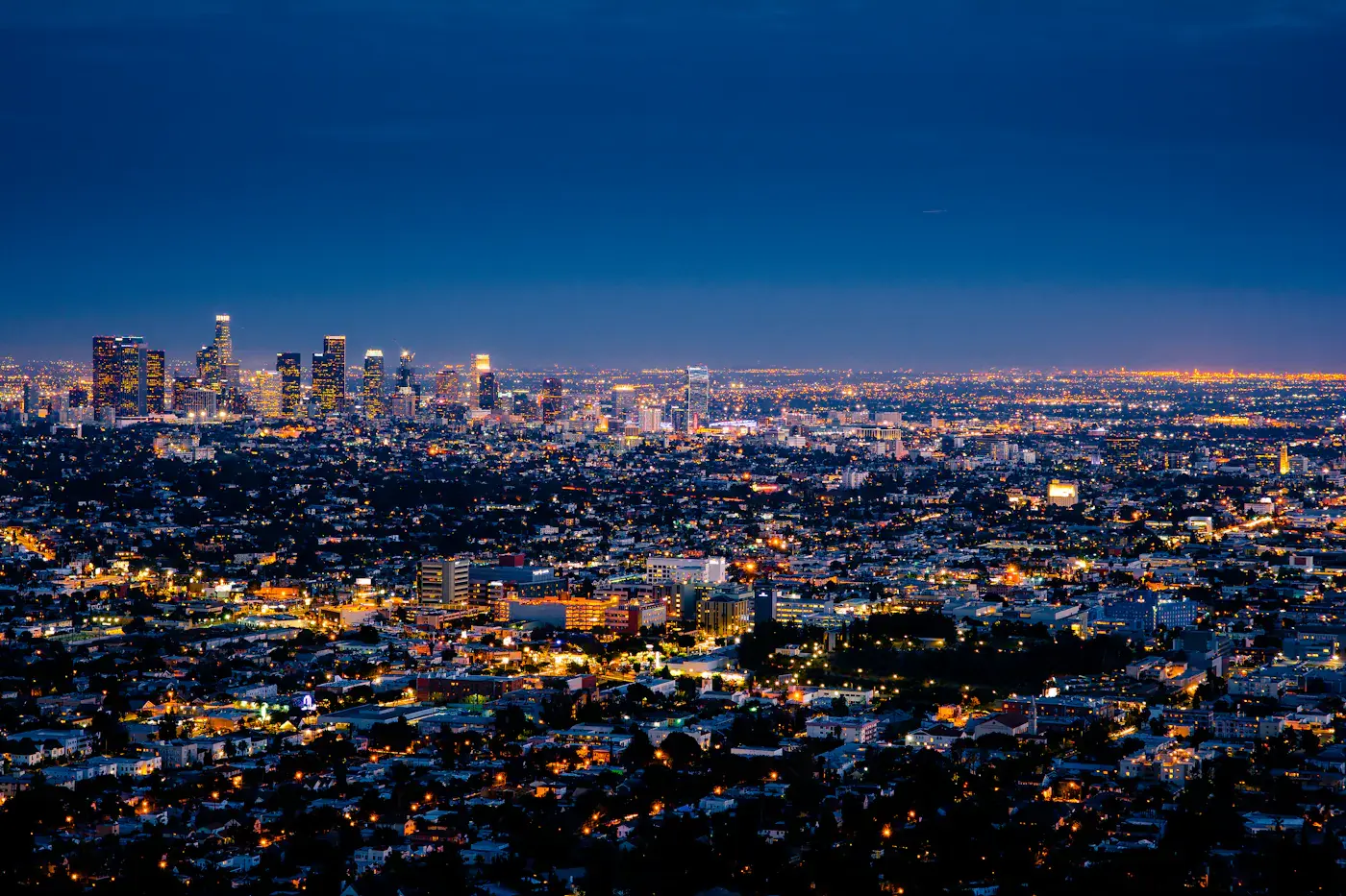 A city skyline at night, its lights spreading across the valley to the horizon