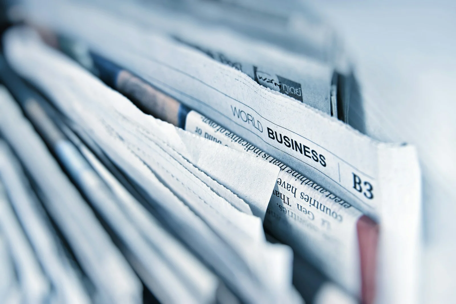 A close-up of folded newspapers stacked together, the World Business section in focus