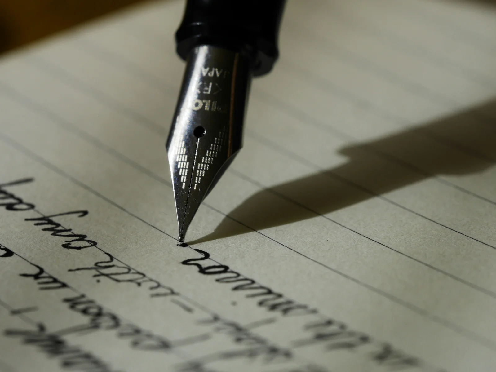 A fountain pen on black lined paper