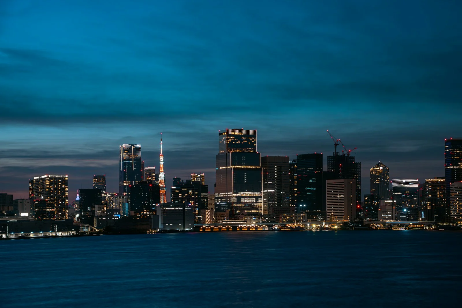 A city skyline lit at dusk over water