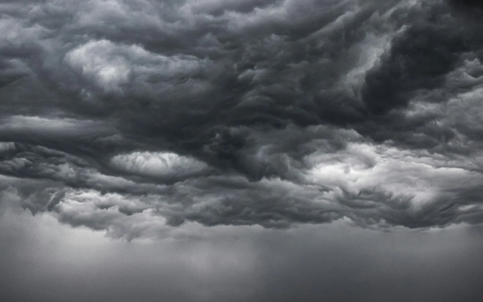 Storm clouds gathering over open ground, in black and white