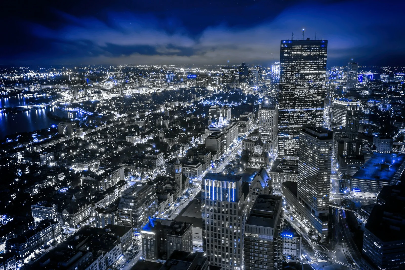 A city at night seen from above, its streets lit in blue