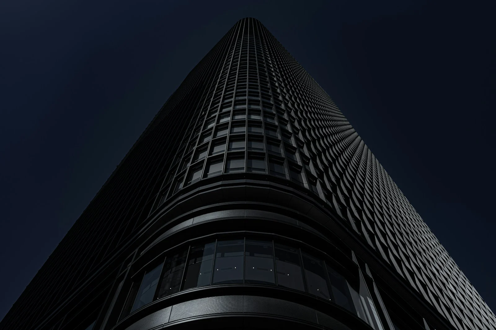 A dark glass tower seen from below against a night sky
